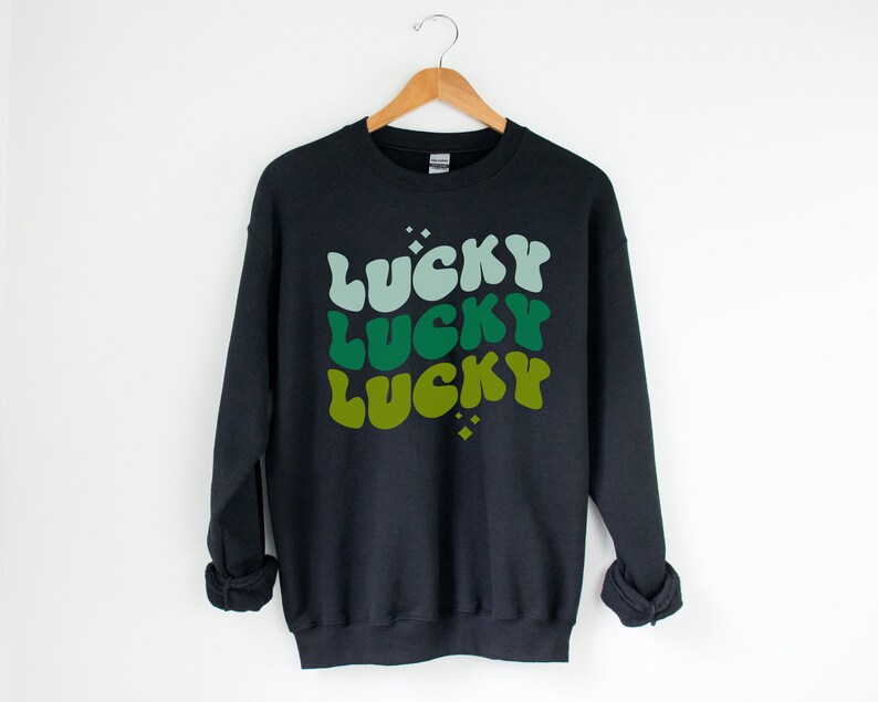 May include: Black sweatshirt with a green, blue, and yellow graphic print that says "Lucky" three times.