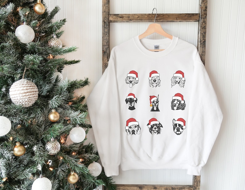May include: White Christmas sweatshirt with a graphic of nine dogs wearing Santa hats. The dogs are all different breeds and are arranged in a grid pattern.