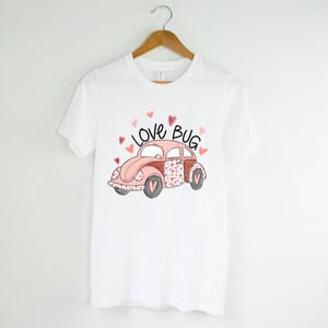 May include: White t-shirt with a pink and red cartoon car with the words "Love Bug" above it.