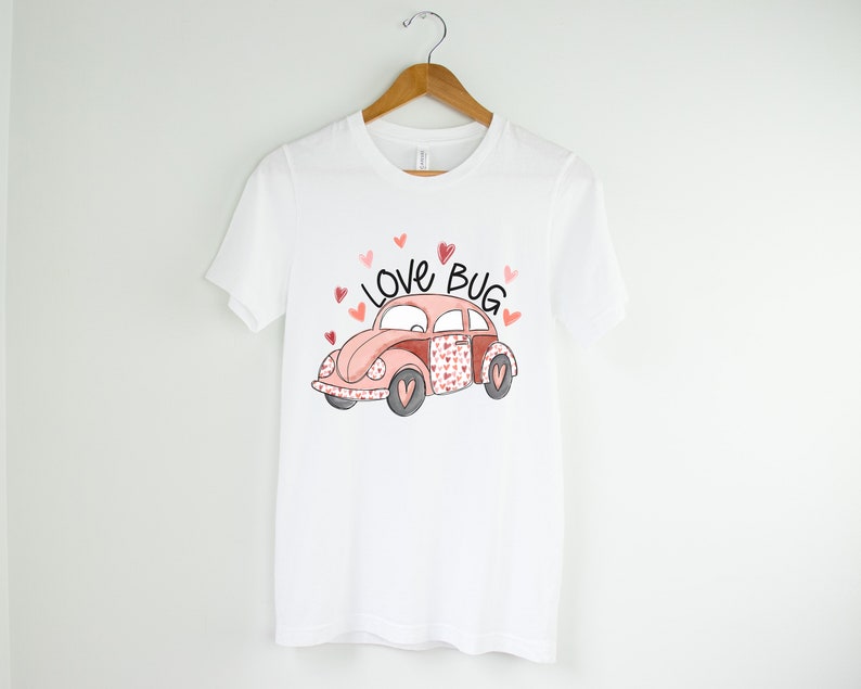 May include: White t-shirt with a pink and red cartoon car with the words "Love Bug" above it.