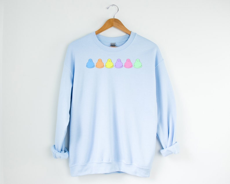 Peut inclure: Sweat-shirt bleu clair avec une rang&eacute;e de six guimauves de dessin anim&eacute; color&eacute;es imprim&eacute;es sur le devant.