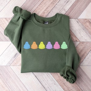 Peut inclure: Un sweat-shirt vert avec une rang&eacute;e de six guimauves color&eacute;es imprim&eacute;es sur le devant.
