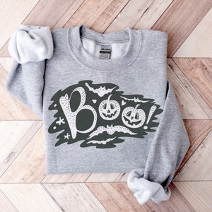 May include: Gray sweatshirt with a white graphic of the word "BOO!" with bats and jack-o'-lanterns.