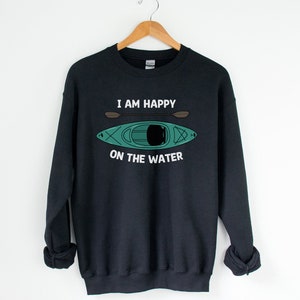 May include: Black sweatshirt with a white graphic print of a kayak and paddles. The text reads "I am happy on the water."