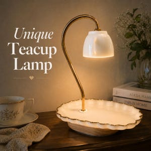 May include: A unique teacup lamp with a white lampshade and a gold-colored, curved support. The lamp sits on a white, scalloped tray with a gold trim. The base is a light brown color. The text "Unique Teacup Lamp" is visible.
