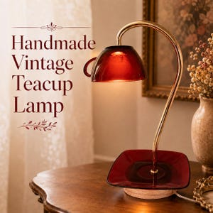 May include: A lamp featuring a deep red glass teacup as the shade and a matching red glass saucer as the base, connected by a curved gold-toned metal arm. The text "Handmade Vintage Teacup Lamp" is displayed on the left side of the image.