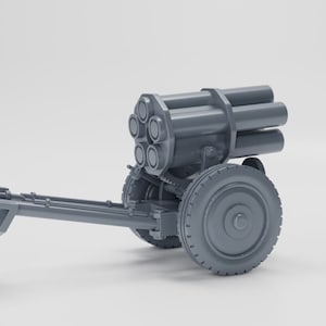May include: A gray metal model of a World War II-era rocket launcher on wheels. The launcher has six barrels and is mounted on a wheeled carriage.