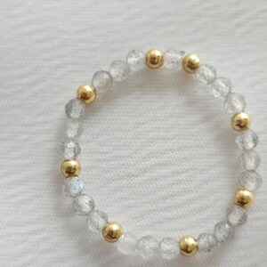 May include: A bracelet made of clear faceted beads with gold accents. The bracelet is made of natural stones and is a beautiful and unique piece of jewelry.