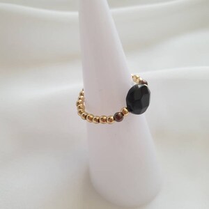 May include: A gold and brown beaded ring with a black faceted gemstone.