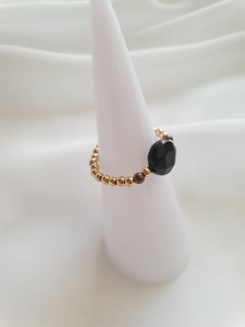 May include: A gold and brown beaded ring with a black faceted gemstone.