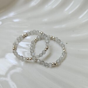 May include: Two silver rings with clear, faceted gemstone beads.