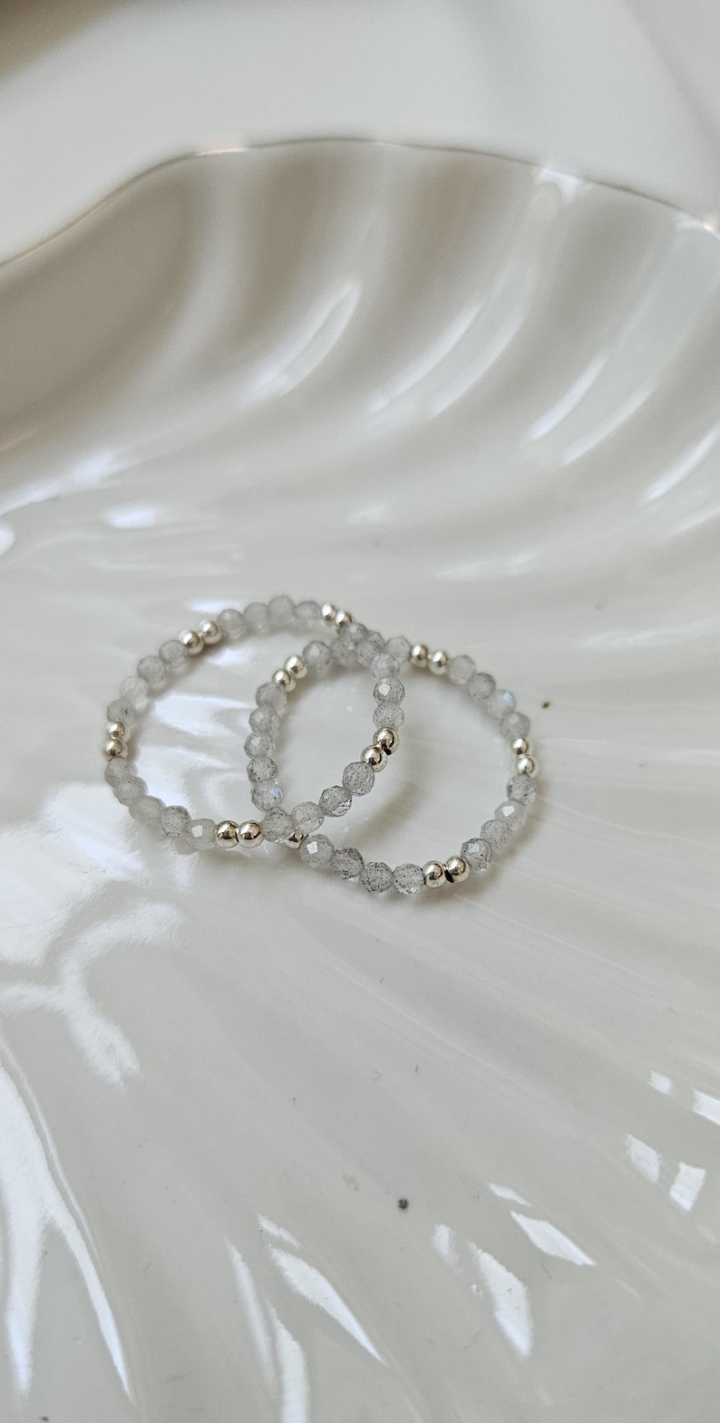 May include: Two silver rings with clear, faceted gemstone beads.