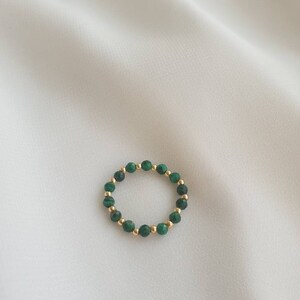 May include: A gold ring with green malachite beads.