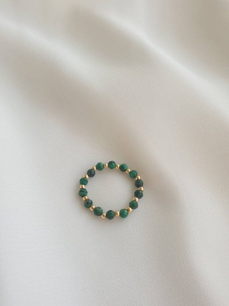 May include: A gold ring with green malachite beads.