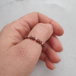 May include: A ring made of small, dark red beads with gold accents.
