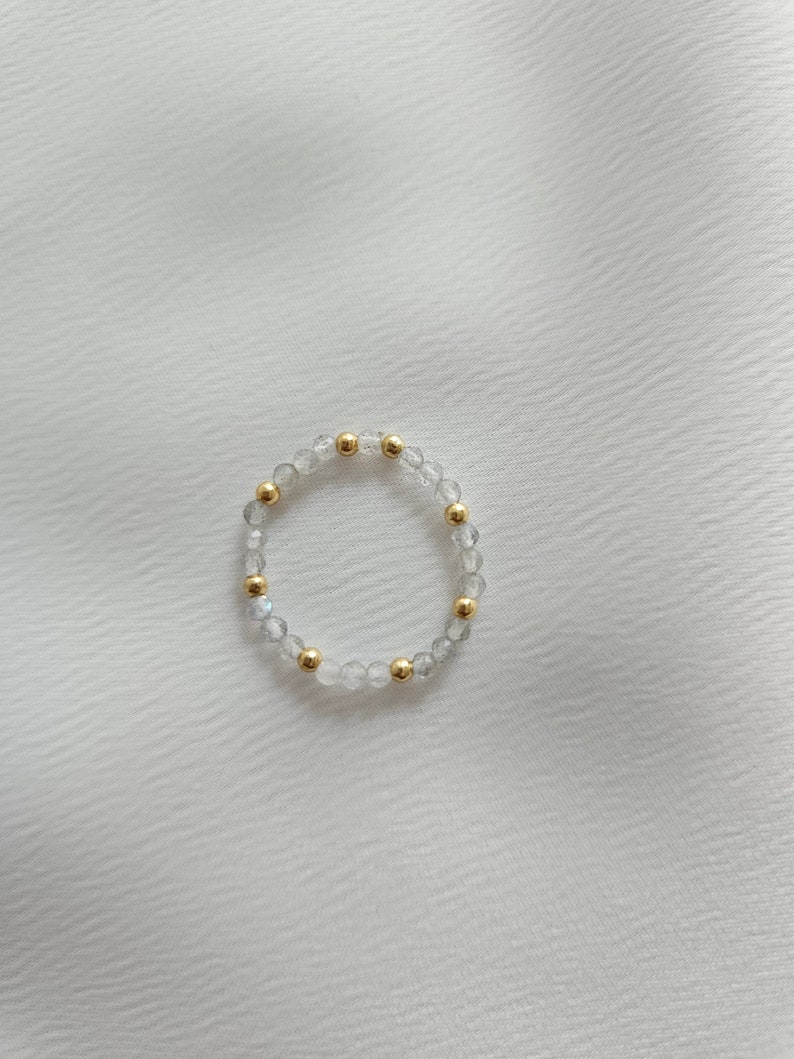 May include: A delicate bracelet made of clear and iridescent beads with gold accents.