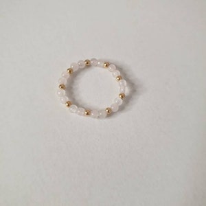 May include: A delicate ring made of small white beads and gold beads.