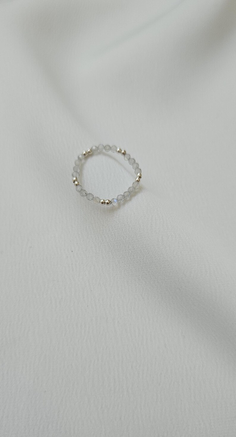 May include: A silver ring with small, clear, faceted beads and silver beads.