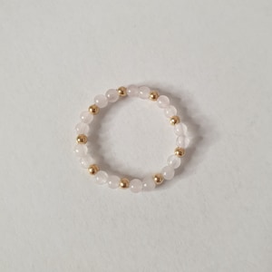May include: A delicate ring made with alternating rose quartz and gold beads.