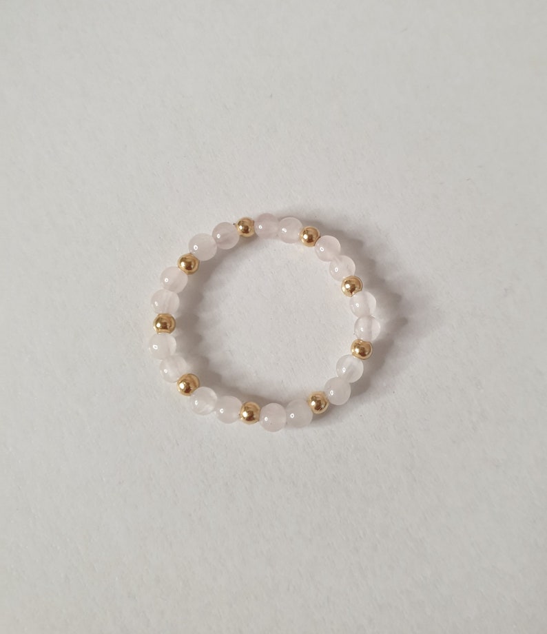 May include: A delicate ring made with alternating rose quartz and gold beads.
