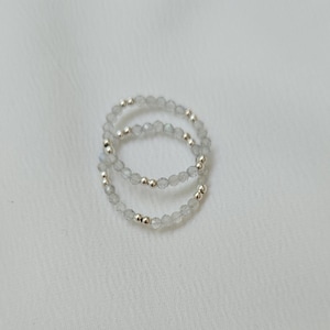 May include: Two silver rings with clear, faceted beads. The rings are stacked on top of each other.