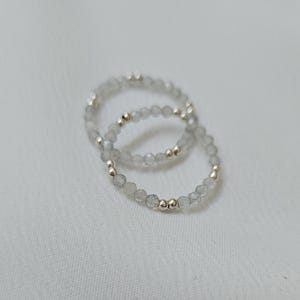 May include: Two silver rings with small, clear, faceted beads and silver beads.