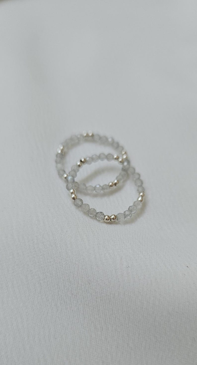 May include: Two silver rings with small, clear, faceted beads and silver beads.