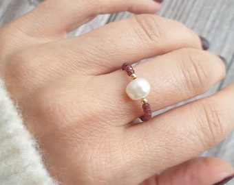 May include: A gold ring with a single white pearl and small red beads.