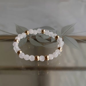 May include: A delicate bracelet made of small, pale pink beads interspersed with gold beads.