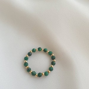 May include: A gold ring with green malachite beads.