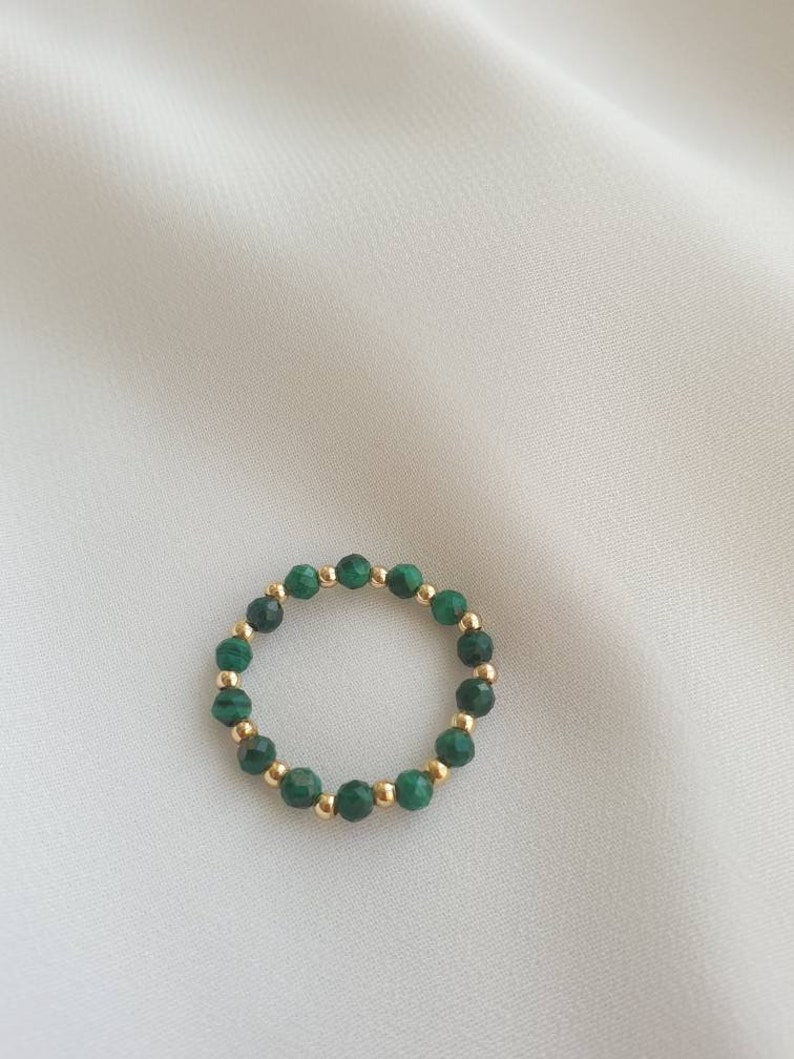 May include: A gold ring with green malachite beads.