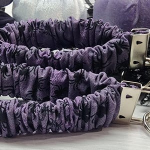 Purple cotton fabric with black spiders design. The keychain uses 7.5 inch to 8 inch wide elastic to make it stretchy. The keychain is completed with silver colored key fob clamps and silver keyring.