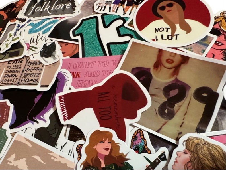 May include: A collection of colorful stickers featuring illustrations and text. Designs include portraits, song lyrics, and the word "folklore". The stickers vary in size and shape, with a mix of bold and pastel colors.
