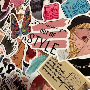 May include: A collection of colorful stickers featuring various designs and text. Stickers include a butterfly, dice, a record, and a portrait of a woman. Text includes "Out of Style", "Angels Roll Their Eyes", and "Devils Roll the Dice".