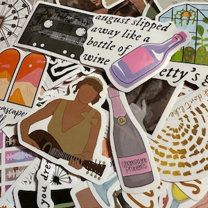May include: A collection of colorful stickers with various designs. One sticker features a bottle of wine with the text "august slipped away like a bottle of wine." Another sticker says "Champagne Problems."