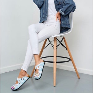 May include: A pair of blue and white sandals with an owl design. The sandals have two straps across the foot and a buckle closure.