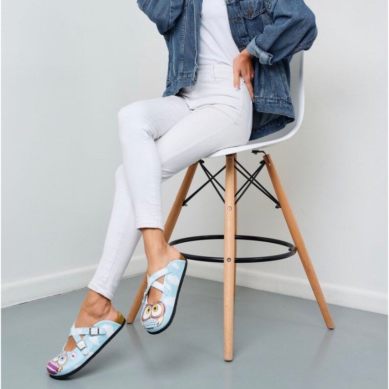 May include: A pair of blue and white sandals with an owl design. The sandals have two straps across the foot and a buckle closure.
