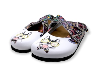 May include: White leather clogs with a colorful, abstract pattern and a cartoon dog wearing sunglasses and a bow tie on the front.