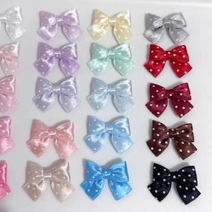 Peut inclure: Collection d'arcs en satin de différentes couleurs, dont rose, bleu et rouge. Chaque nœud présente un motif à pois. Les nœuds sont disposés de près, mettant en valeur leur variété.
