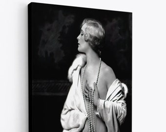 Op de afbeelding: Zwart-wit kunstafdruk van een vrouw in vintage stijl. Ze draagt een witte badjas met een bontkraag en een lange parelketting. De afbeelding is een klassiek portret.