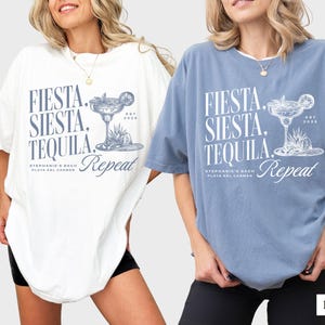 Puede incluir: Dos camisetas de gran tama&ntilde;o con un dise&ntilde;o gr&aacute;fico azul que dice "Fiesta, Siesta, Tequila, Repeat" con una ilustraci&oacute;n de vaso de margarita. La camiseta de la izquierda es blanca y la camiseta de la derecha es azul vaquero.