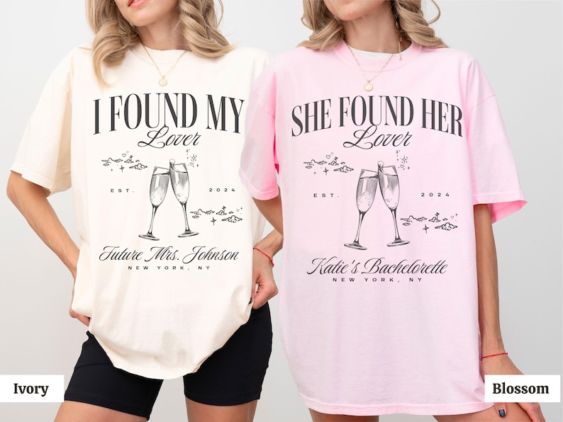 May include: Two women wearing oversized t-shirts with a hen party theme. The shirts are in ivory and pink with black text that reads "I Found My Lover" and "She Found Her Lover". Both shirts feature a graphic of two champagne glasses with the text "EST. 2024" and "Future Mrs. Johnson" or "Katie's Bachelorette" below.