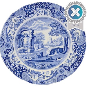 Puede incluir: Un plato de cerámica azul y blanco con un diseño escénico que presenta un puente, árboles y un edificio. El plato tiene un borde decorativo con patrones florales y geométricos.