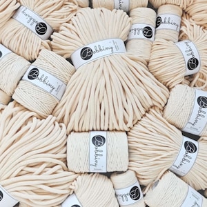 May include: A close-up of several spools of natural colored cotton rope, each labeled "Bobbiny 5mm".