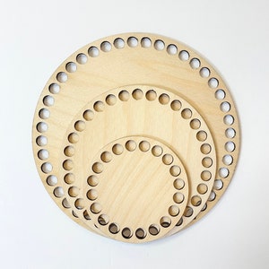 May include: Three round wooden crochet hoops of different sizes. The hoops are made of light brown wood and have evenly spaced holes around the edges.