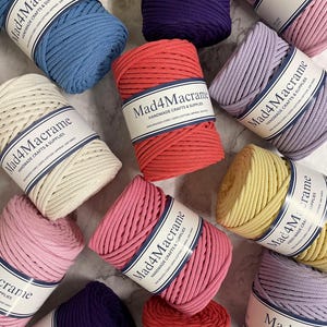 May include: An overhead shot of several spools of Mad4Macrame brand braided cord in various colors, including blue, pink, red, purple, yellow, and cream. Each spool is labeled with the brand name and product details.