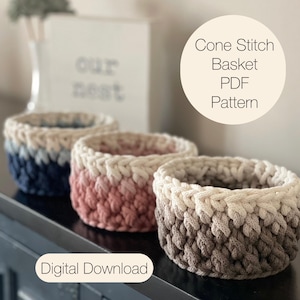 May include: Three handmade crochet baskets in a row, each with a unique color gradient. The baskets are in shades of blue, pink, and brown, with a white top border. The image also includes text that says "Cone Stitch Basket PDF Pattern" and "Digital Download".
