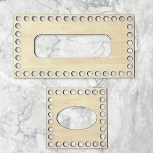 May include: Two wooden loom knitting boards with circular holes around the edges. The larger board has a rectangular opening in the center, while the smaller board has an oval opening.