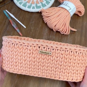 May include: Peach-colored crochet basket with a "Handmade" tag, alongside a matching coaster with white, mint, and peach accents. A ball of peach-colored yarn and crochet hooks complete the craft supplies.