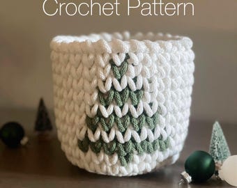 May include: A white crochet basket featuring a green Christmas tree motif. The text "Crochet Pattern" is at the top, and "PDF & Video Tutorial Included" is at the bottom. Christmas decorations surround the basket.